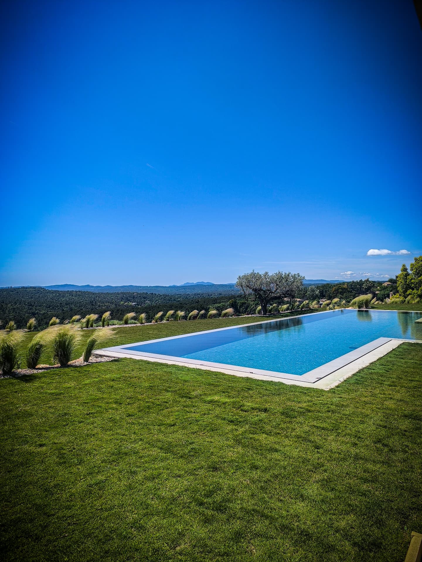 Jardin avec piscine à débordement et vue sur les collines